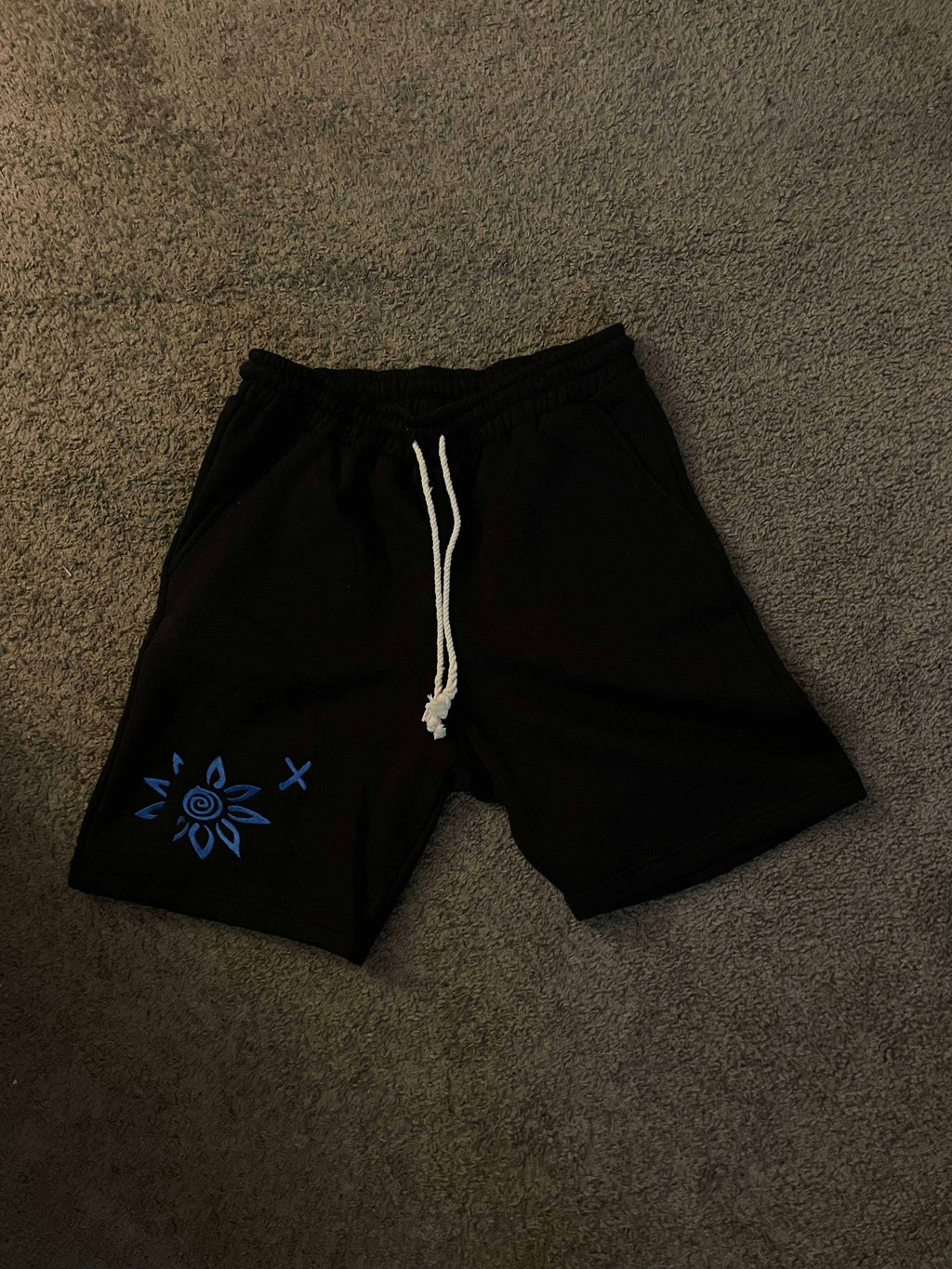 Black shorts with blue embroidered WISE FLOWER X design and white beach rope drawstring