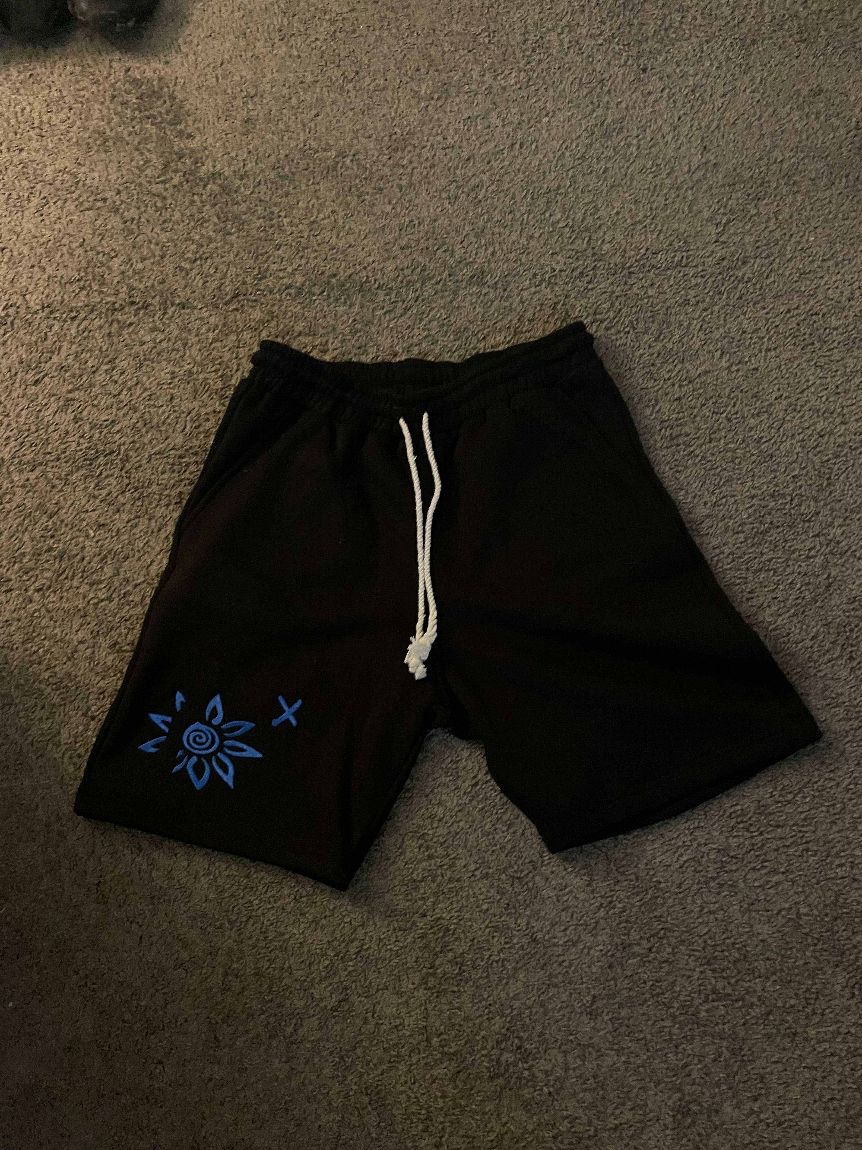 Black shorts with blue embroidered WISE FLOWER X design and white drawstring waistband