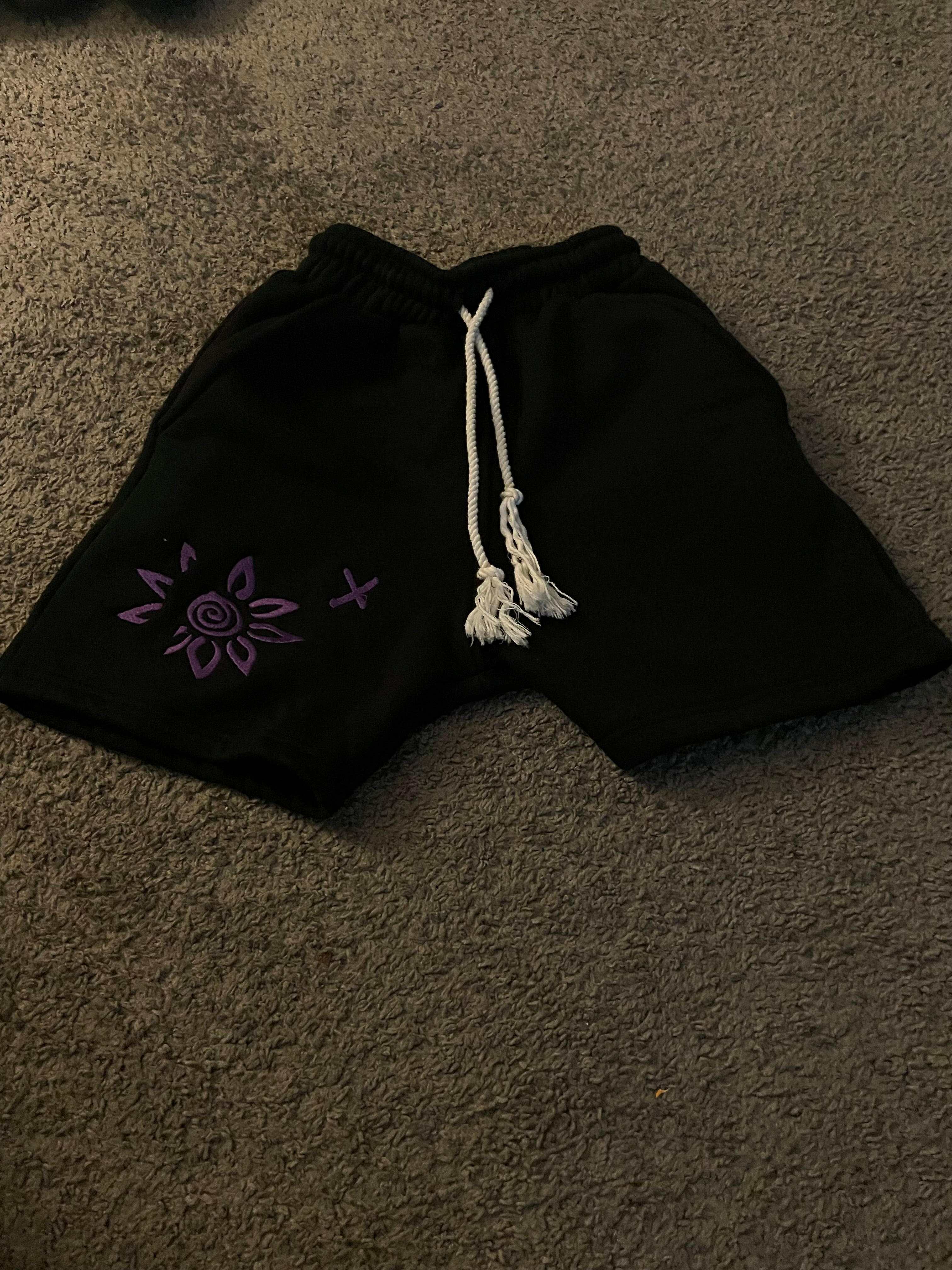 Black shorts with purple embroidered wise flower x design and white drawstring waistband