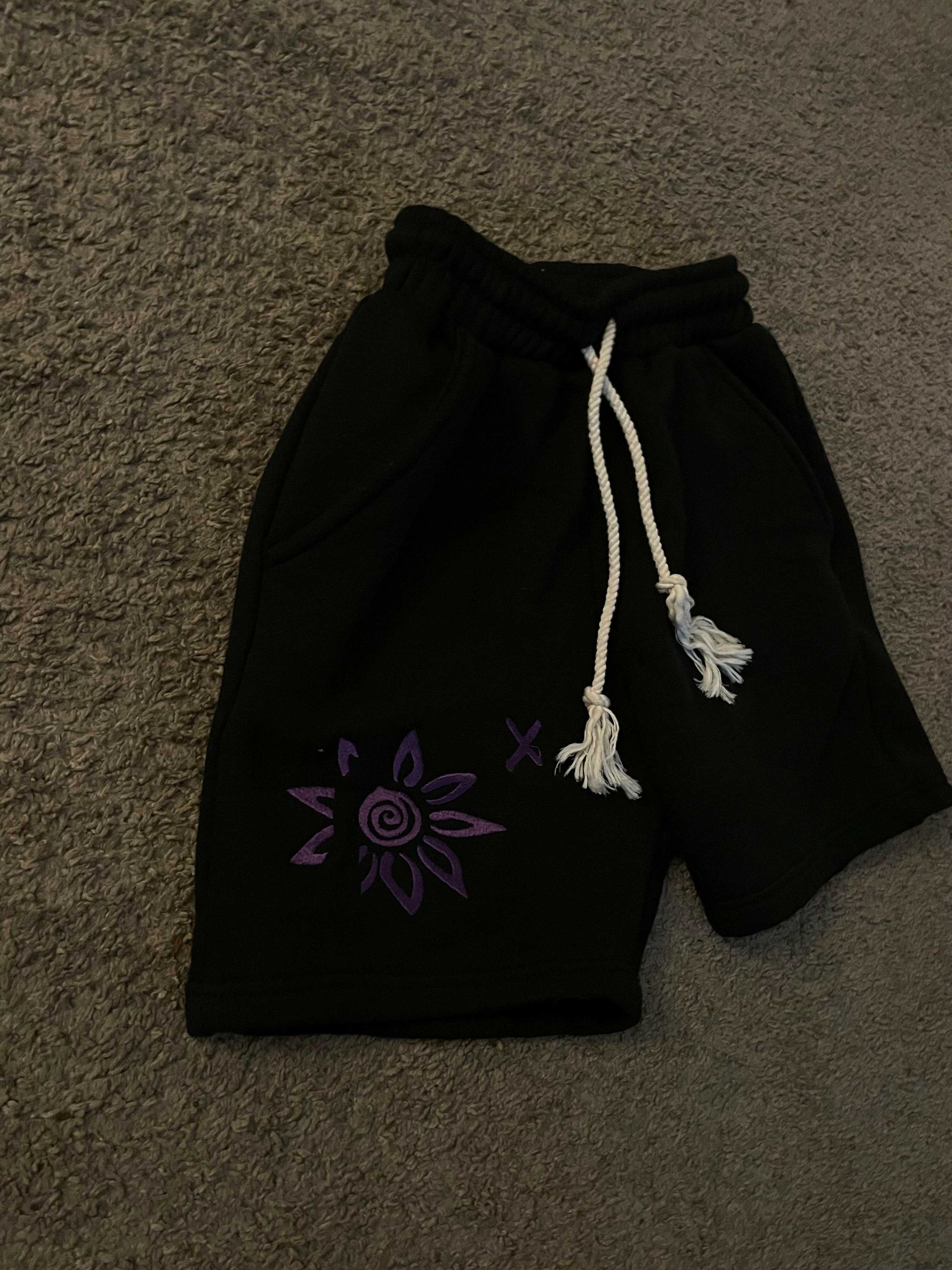 Black shorts with purple Wise Flower X embroidered design and white drawstrings