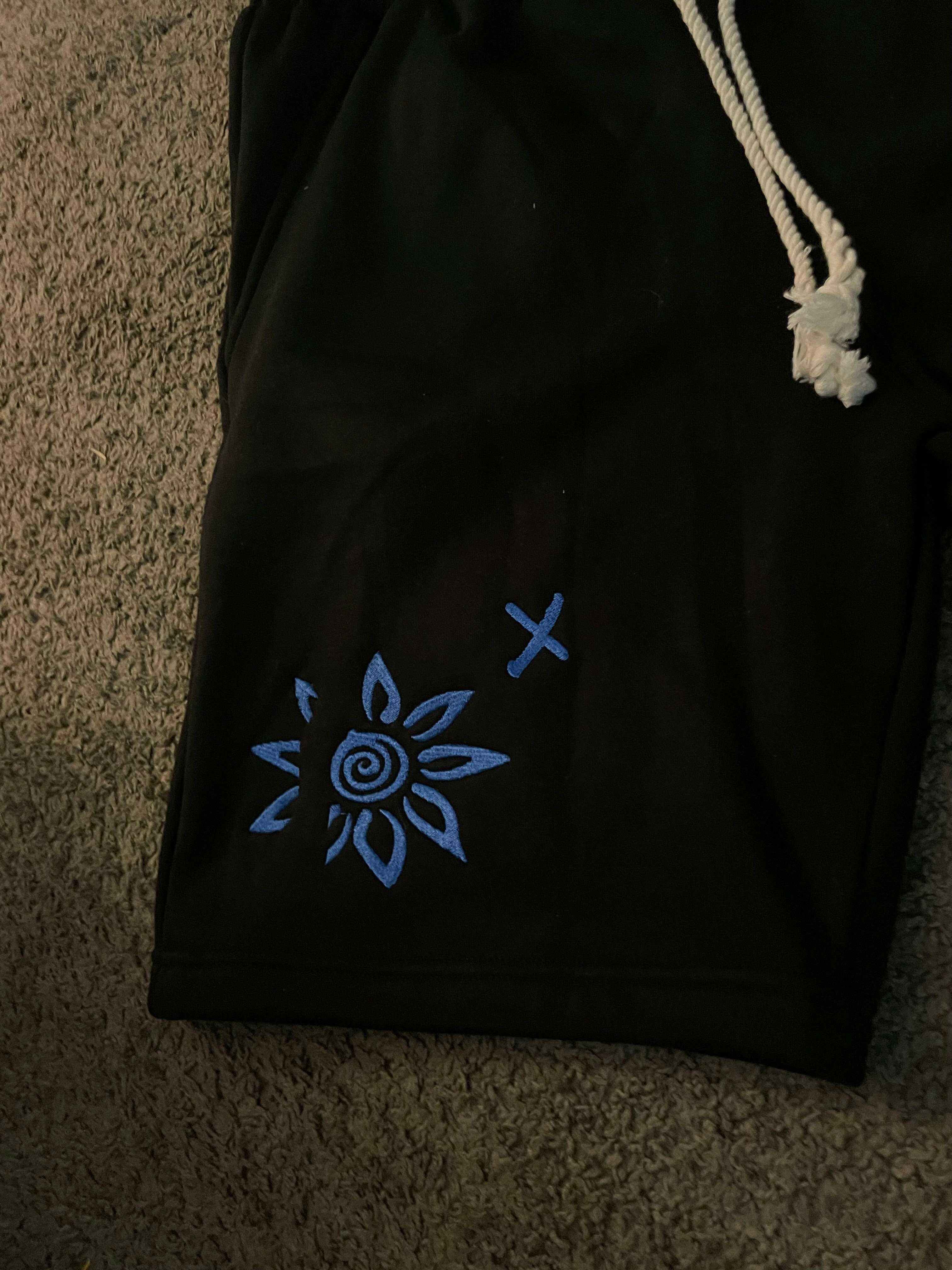 Black shorts with blue embroidered WISE FLOWER X design and white beach rope drawstring