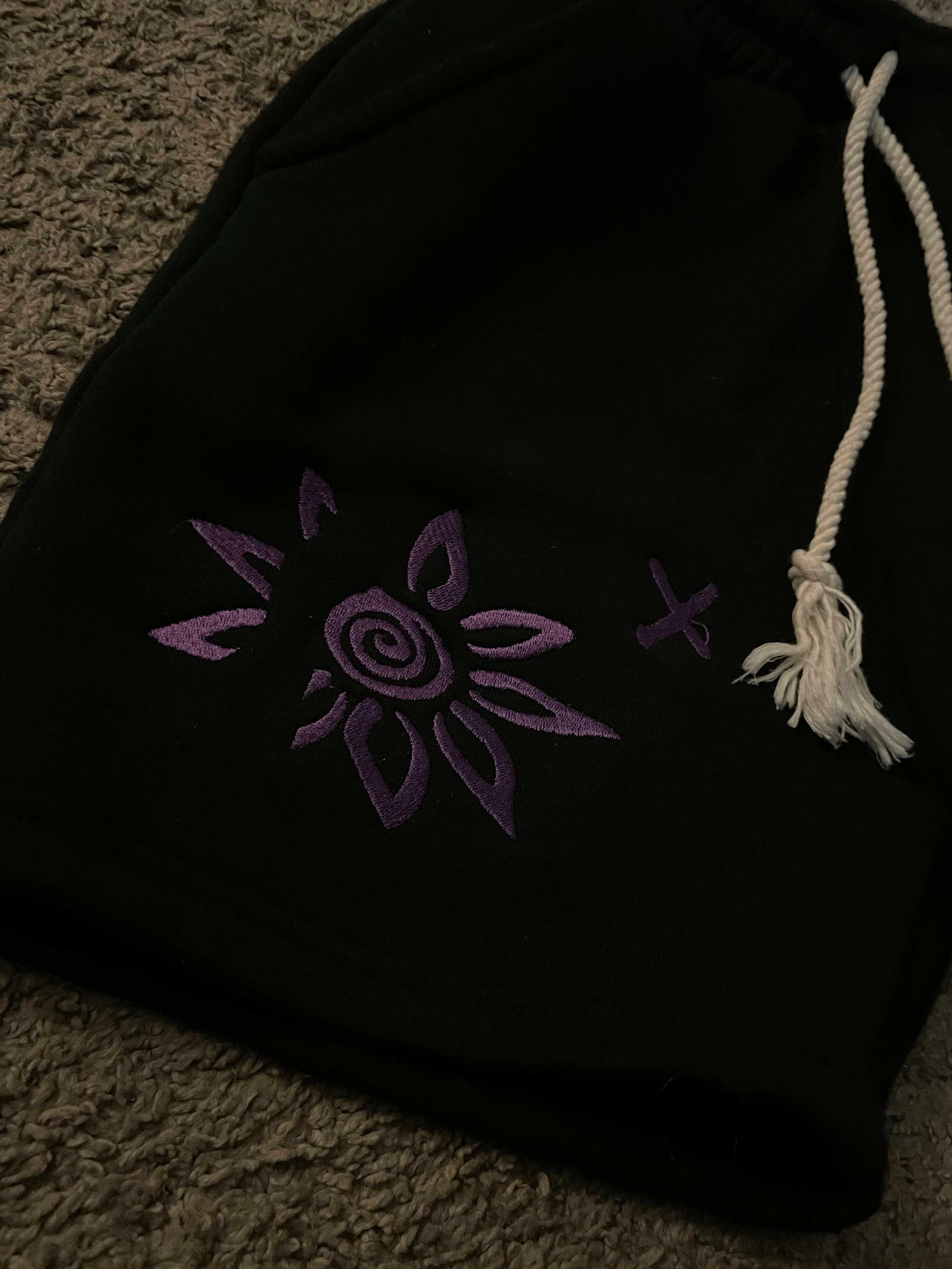 Black shorts with purple embroidered Wise Flower X design and white drawstring rope