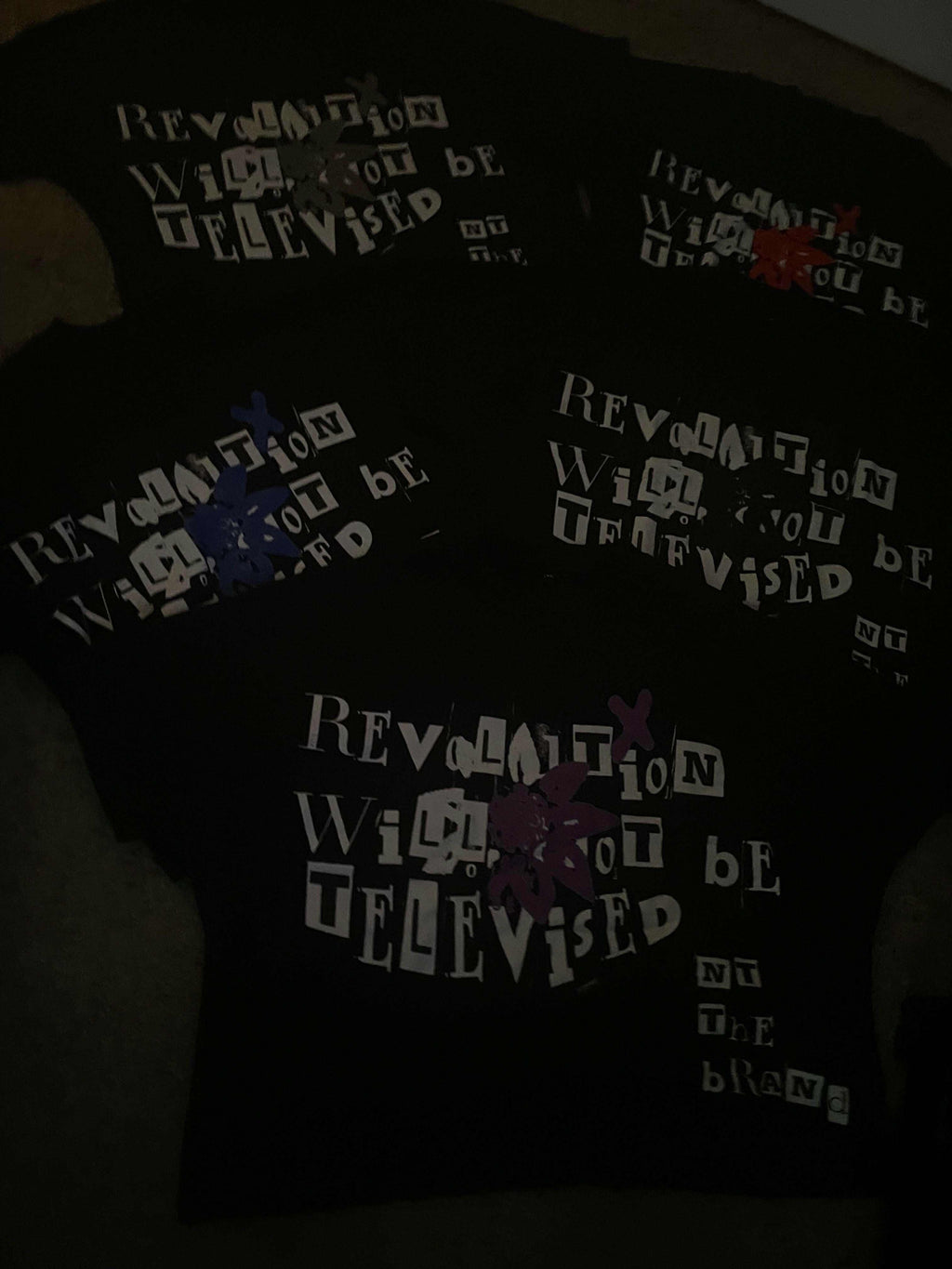Set of black Revolution bundle T-shirts with "Revolution will not be televised" text and colorful flower x symbols on each shirt